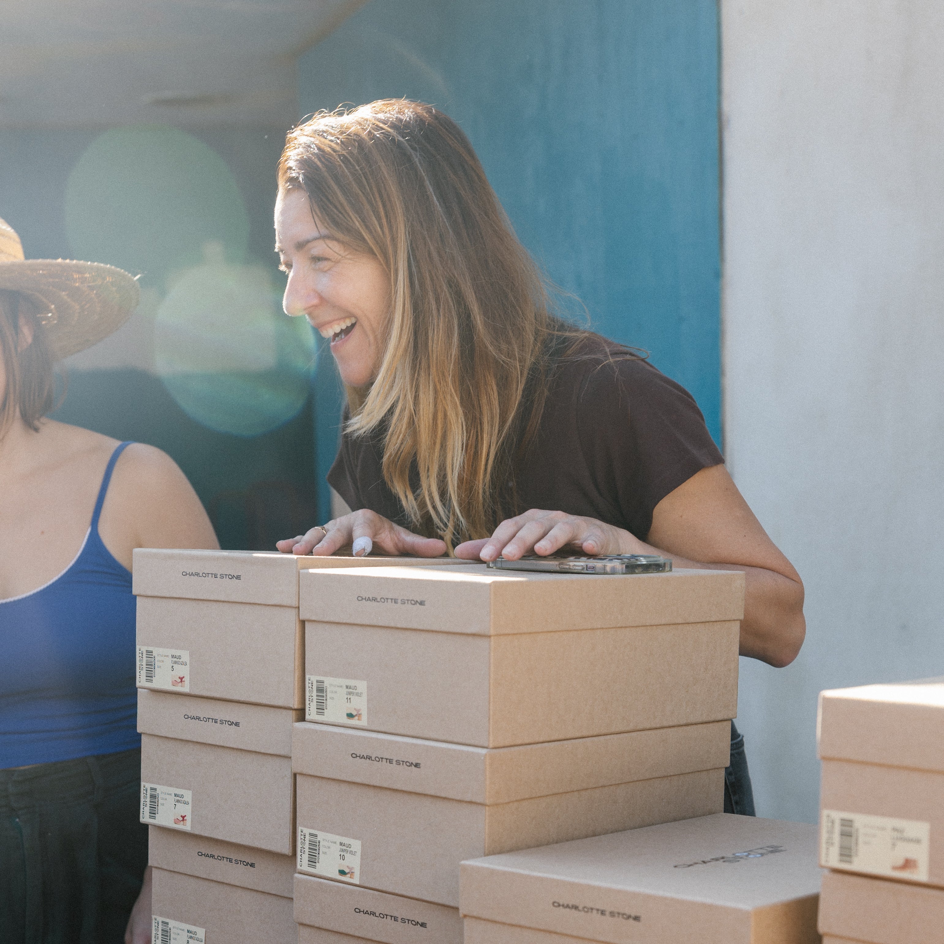 Woman looking at stacks of shoe boxes with various shoes displayed in front.