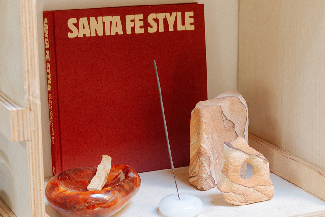 Wooden shelf with a red book titled 'Santa Fe Style', a small bowl, and a wooden sculpture.