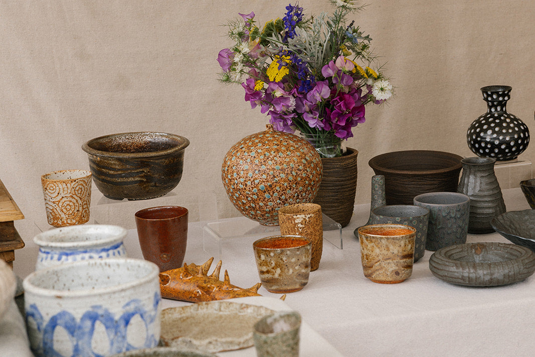 Table with various ceramic items and a bouquet of flowers against a beige background