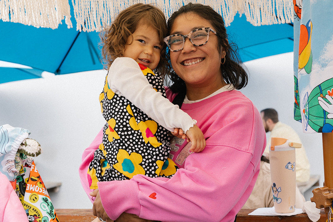 Woman holding a child in a colorful clothing store