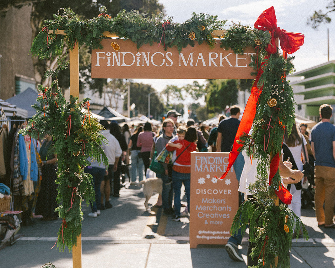 Decorative entrance to a market with festive greenery and a sign reading 'Findings Market'.